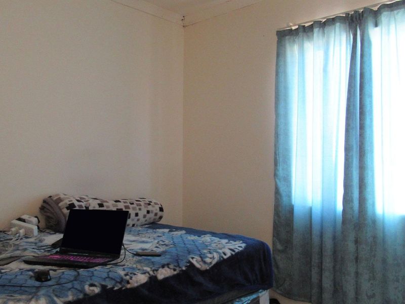 A simple bedroom featuring a window with installed curtain rods, providing natural light and a functional space for rest.