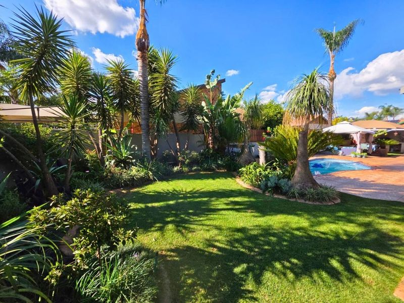A well-maintained outdoor area featuring a swimming pool, paved patio space, and established garden landscaping.