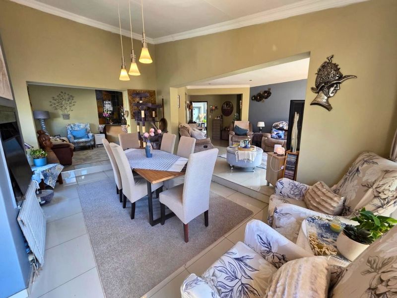 Spacious open-plan living and dining area featuring split-level tiled flooring, coved cornicing, and modern pendant lighting, creating a versatile multi-functional space.
