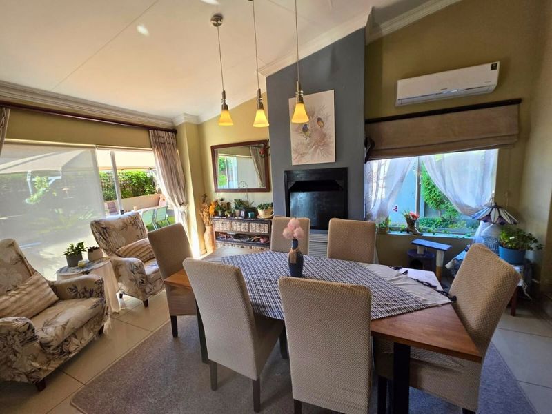 A bright dining room featuring a built-in fireplace, split-system air conditioning, tiled flooring, and large sliding glass doors providing natural light and garden access.