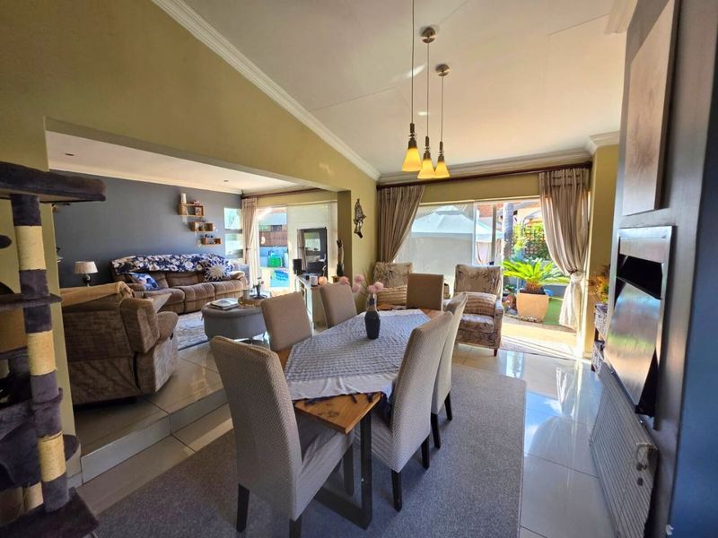Spacious open-plan living and dining area featuring tiled floors, a built-in fireplace, and large sliding doors providing natural light and access to the patio.