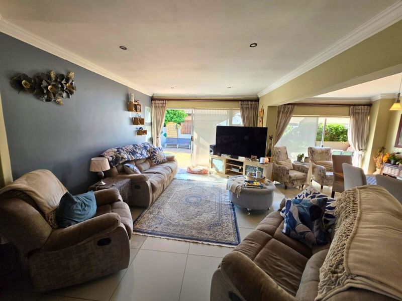 Spacious open-plan living area featuring tiled flooring, recessed downlighting, and large sliding glass doors providing access to the outdoor space.