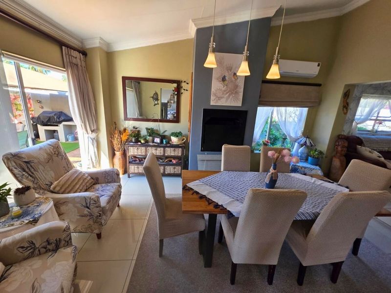 Open-plan living and dining area featuring a fireplace, split-system air conditioning, and direct access to an outdoor patio through sliding glass doors.