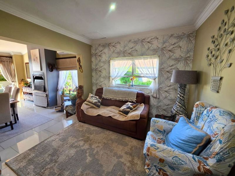 A cozy living room featuring tiled flooring, crown molding, and a built-in fireplace, with an open-plan flow into the adjacent dining area.