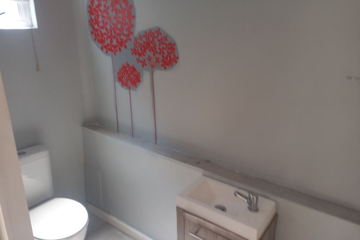 A compact bathroom featuring a modern vanity basin with a mixer tap and a standard toilet, finished with neutral wall tones.