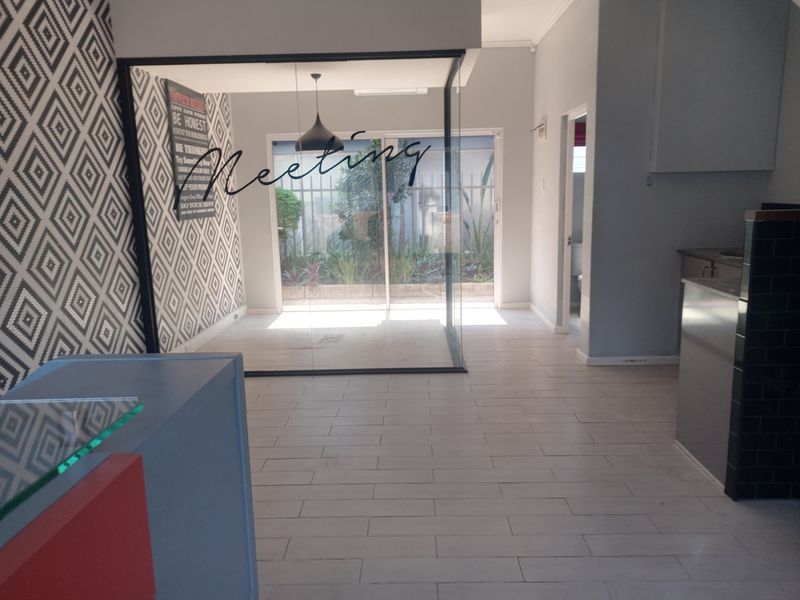 A modern commercial office space featuring a glass-enclosed meeting room, tiled flooring, and a reception area with contemporary finishes.