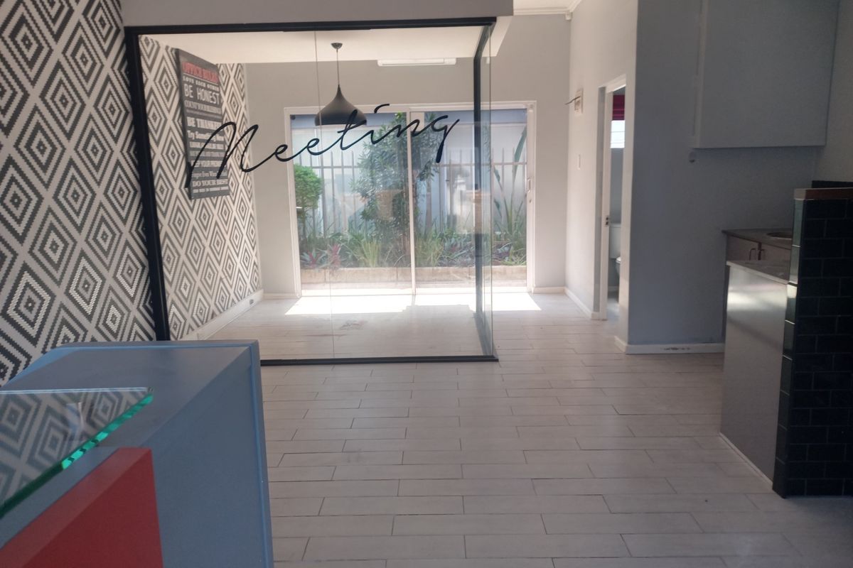 A modern commercial office space featuring a glass-enclosed meeting room, tiled flooring, and a reception area with contemporary finishes.