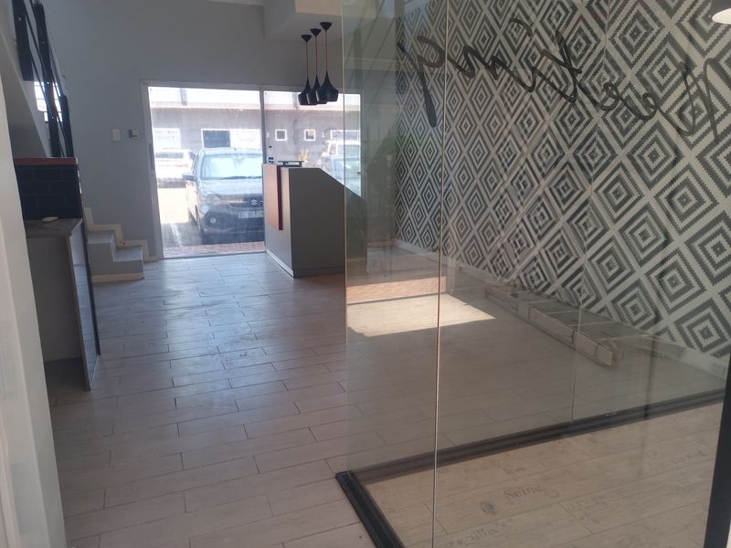 Modern commercial entry area featuring tiled flooring, a glass partition, and a built-in reception desk with contemporary pendant lighting.