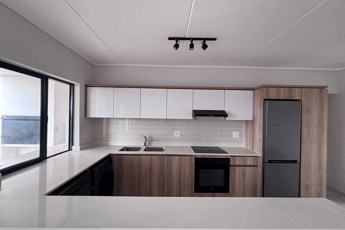 Modern kitchen featuring sleek wood-tone and white cabinetry, quartz countertops, integrated appliances, and a stylish subway tile backsplash.