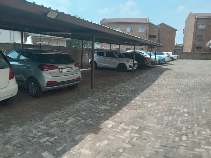 A functional outdoor covered parking area with paved surfacing and perimeter walling within an apartment complex.