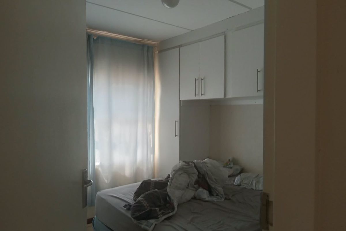 A bedroom featuring built-in cupboards and overhead storage cabinets, providing functional storage space within the room.