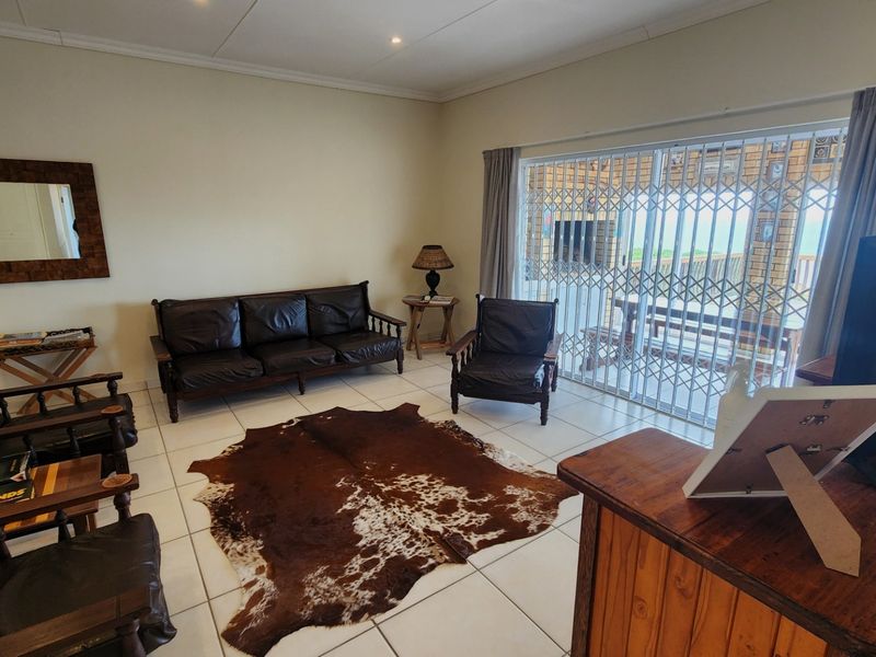 Spacious living room featuring neutral tiled flooring, recessed lighting, and a large sliding glass door providing access to the outdoor patio area.