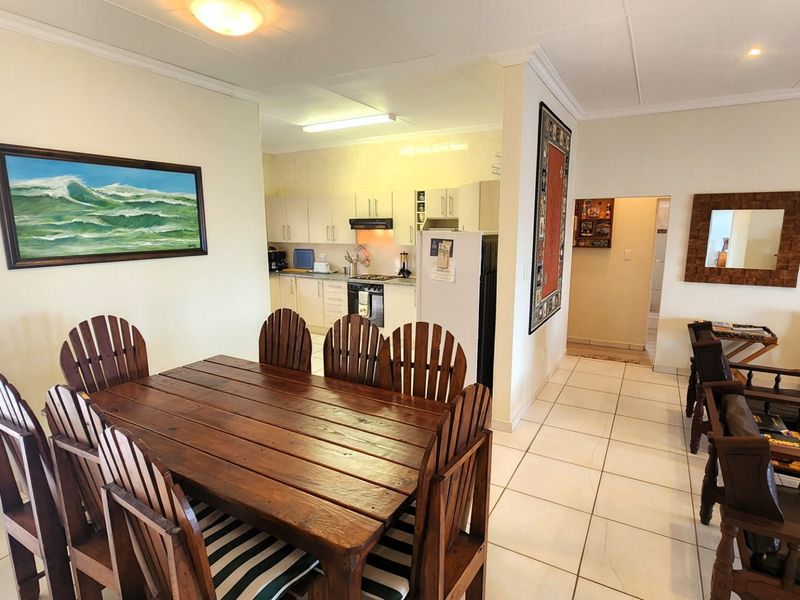 Open-plan living and dining area featuring tiled flooring and a functional kitchen with built-in cabinetry, oven, and hob.