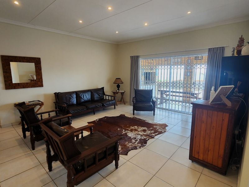 Spacious living room featuring tiled flooring, recessed downlighting, and a sliding glass door with security gate leading to the outdoor area.