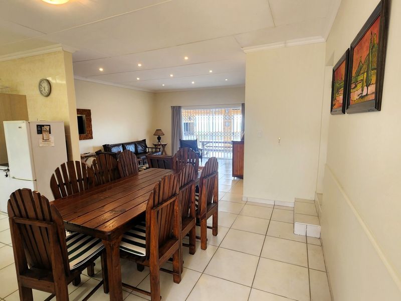 Open-plan living and dining area featuring tiled flooring, recessed lighting, and a sliding glass door leading to the exterior.