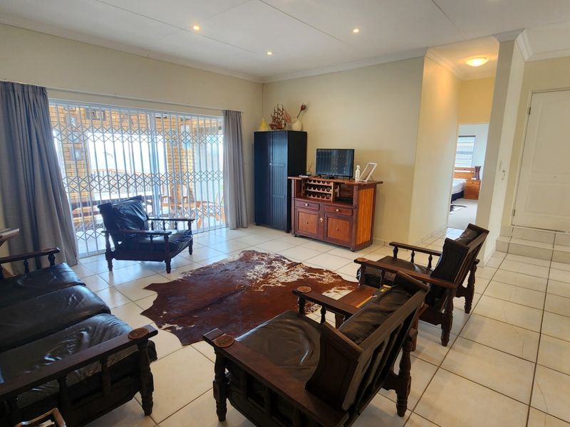 Spacious living area featuring neutral tiled flooring, recessed lighting, and a sliding glass door providing access to the outdoor patio area.