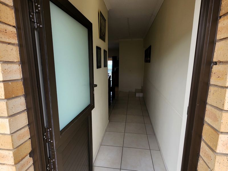Entrance hallway featuring ceramic floor tiles and a frosted glass door, leading into the main living area of the home.