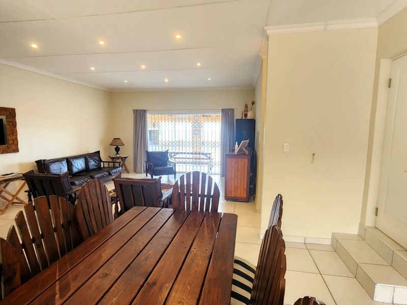 Spacious open-plan living and dining area featuring tiled flooring, recessed downlighting, and direct access to the outdoor patio through a sliding glass door.