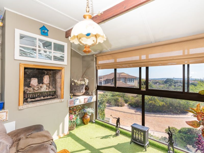 Enclosed balcony or sunroom featuring a built-in fireplace, large windows with neighborhood views, and an exposed timber beam ceiling.