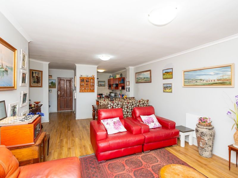 Open plan living and dining area featuring laminate flooring and a connected kitchen space with built-in cabinetry.