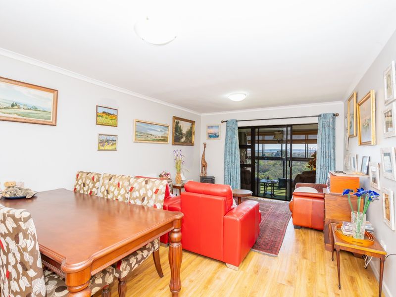 Spacious open-plan living and dining area featuring laminate flooring and large sliding glass doors leading to an outdoor balcony with scenic views.