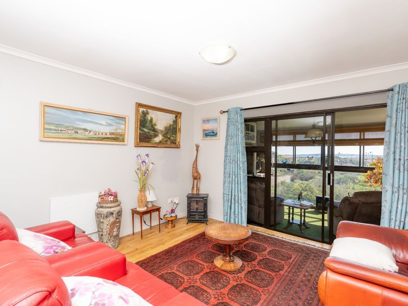 A comfortable living room featuring laminate flooring and a large sliding glass door that provides access to an outdoor balcony area.