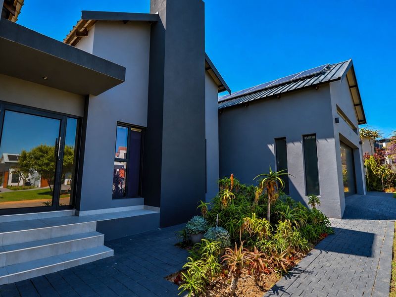 Modern front elevation featuring a paved driveway, solar panels, and a contemporary entrance with tiled steps.