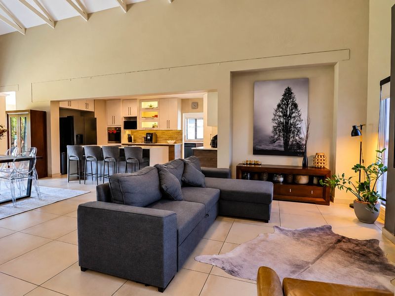 Spacious open-plan living area featuring a vaulted ceiling, tiled floors, and a modern kitchen with a central island and integrated appliances.
