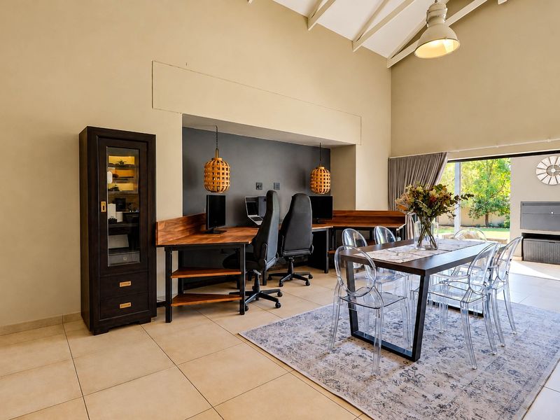 Spacious open-plan living area featuring a vaulted ceiling, tiled floors, and a dedicated built-in workspace, seamlessly connecting to the outdoor patio area.