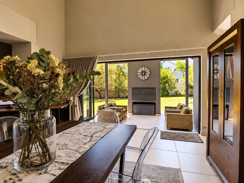 Spacious open-plan living area featuring high ceilings, large sliding doors opening to a patio, and a built-in fireplace, creating a seamless indoor-outdoor flow.