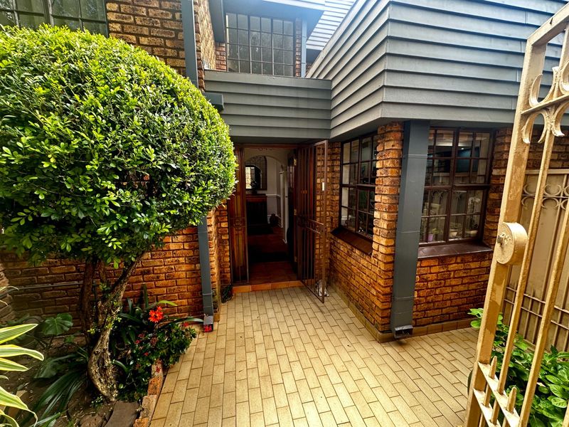 Front entrance of the townhouse featuring a paved walkway, brick facade, and secure metal gate access.