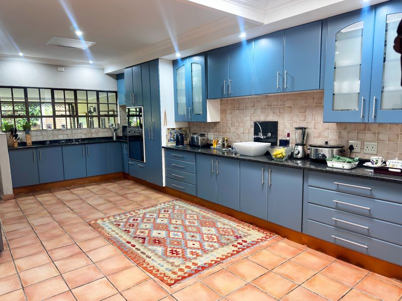 Spacious kitchen featuring blue cabinetry, granite countertops, a built-in oven, and ceramic tile flooring, offering ample storage and workspace.