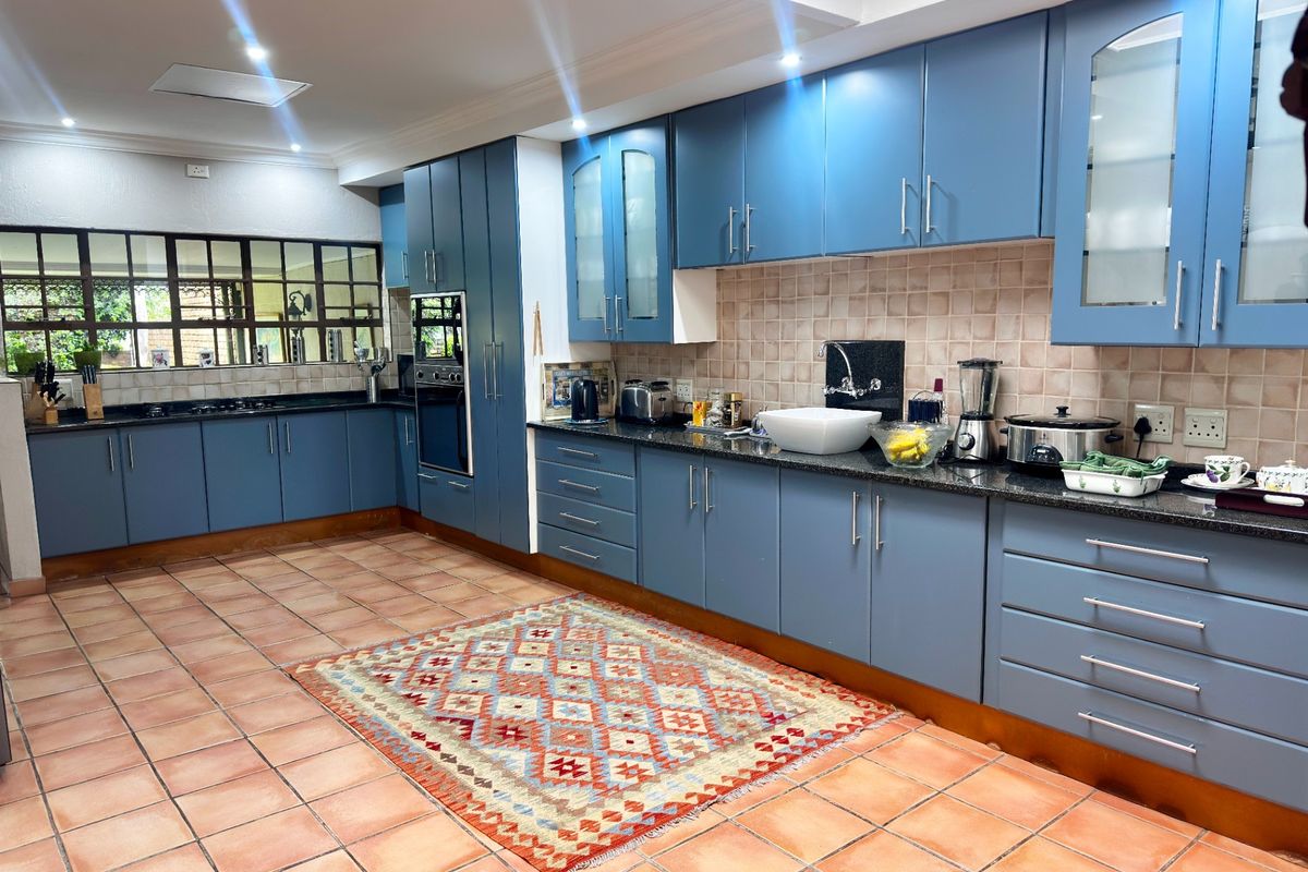 Spacious kitchen featuring blue cabinetry, granite countertops, a built-in oven, and ceramic tile flooring, offering ample storage and workspace.
