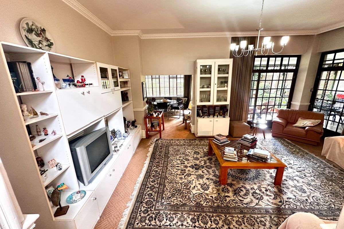 Spacious living room featuring built-in cabinetry, crown molding, and large glass french doors leading to an outdoor area.