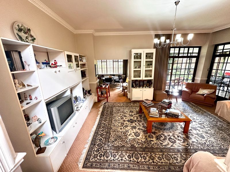 Spacious living room featuring built-in cabinetry, crown molding, and large glass french doors leading to an outdoor area.