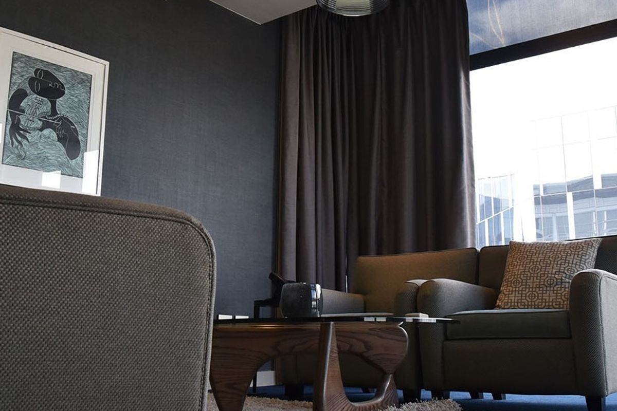 A modern, well-appointed living area featuring dark textured walls, large windows with floor-to-ceiling curtains, and contemporary recessed lighting.