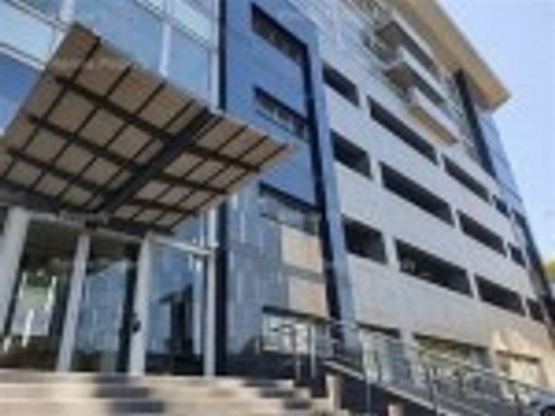 Modern commercial building facade featuring a glass curtain wall, prominent metal entrance canopy, and sleek cladding, showcasing a professional and contemporary architectural design.