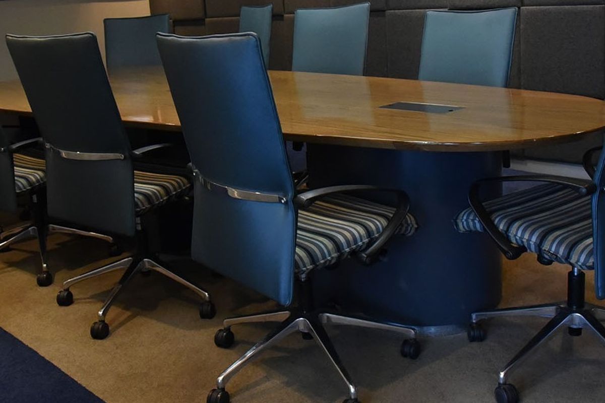 A professional boardroom featuring a large oval meeting table with integrated cable management and acoustic wall paneling for sound control.