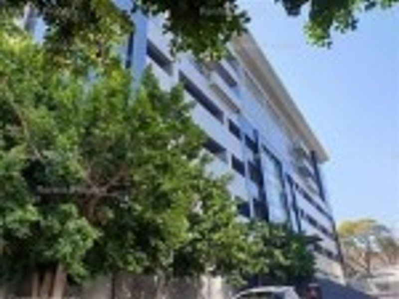 A low-angle view of a modern multi-story commercial building featuring a glass curtain wall facade and aluminum framing.
