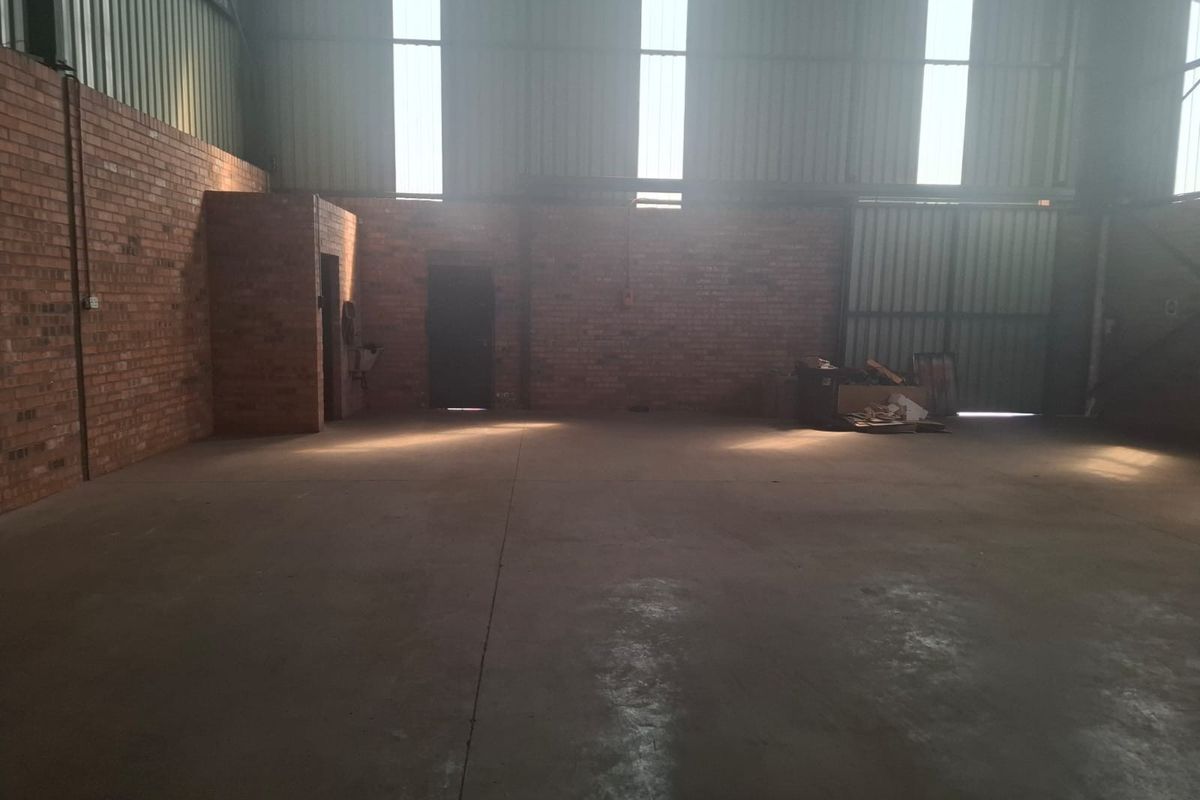 Spacious industrial utility area featuring exposed brick walls, durable concrete flooring, and high ceilings with natural light from translucent roof panels.