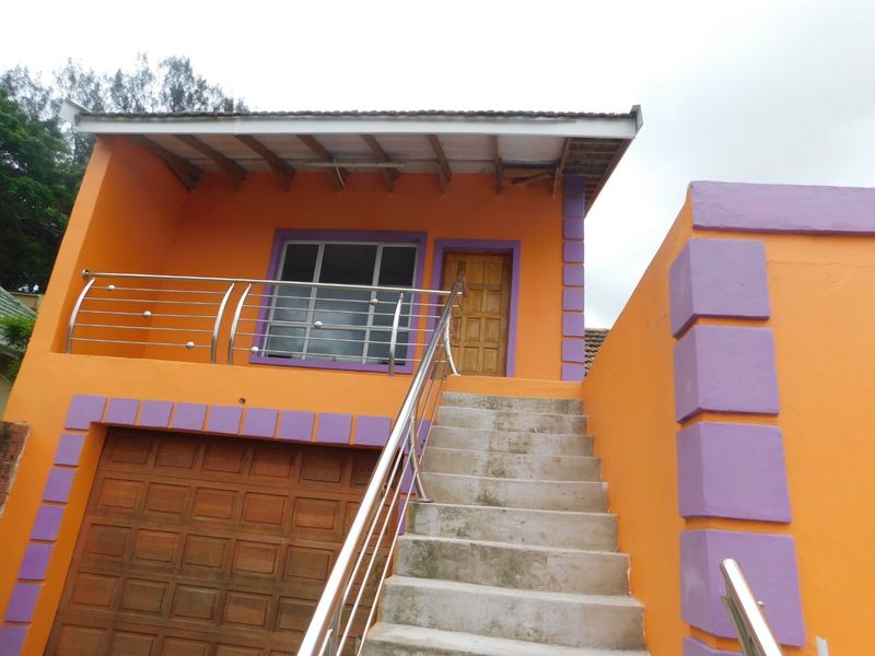 Front exterior view of a cottage featuring a concrete staircase with stainless steel balustrades, a garage, and a timber entrance door.