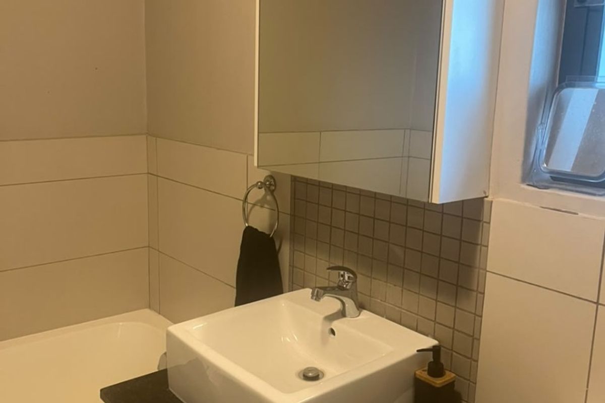 A functional bathroom featuring a modern vessel sink on a stone vanity, a mirrored medicine cabinet, and a standard bathtub with tiled wall finishes.