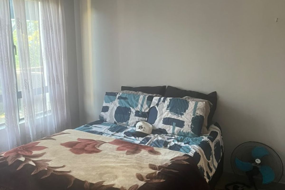 A functional bedroom featuring tiled flooring, neutral wall finishes, and natural light through a window with curtain fixtures.