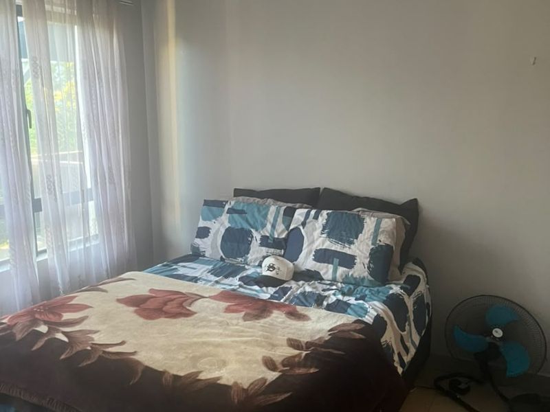 A functional bedroom featuring tiled flooring, neutral wall finishes, and natural light through a window with curtain fixtures.