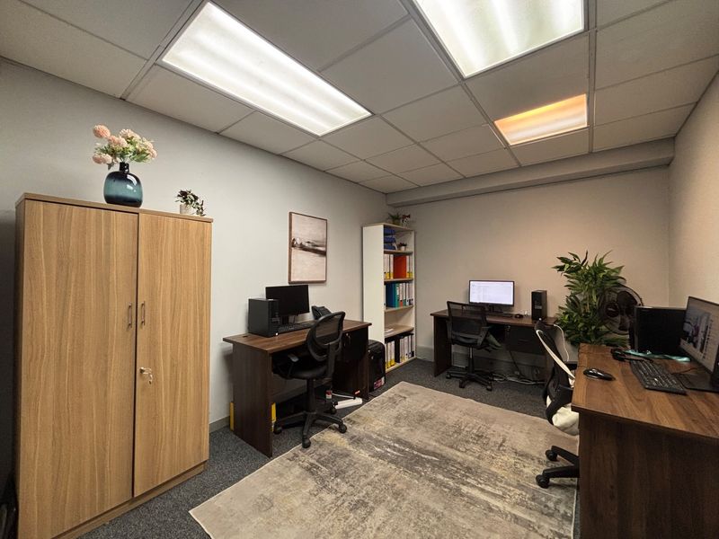 A functional office space featuring a suspended ceiling with recessed lighting and carpeted flooring, suitable for a professional work environment.