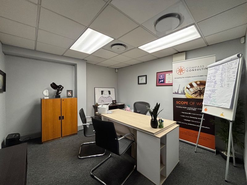 A functional office space featuring a suspended ceiling with recessed lighting and carpeted flooring, suitable for professional use.