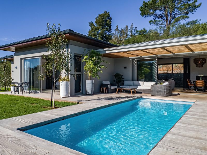 Modern outdoor living area featuring a swimming pool, timber decking, and a covered patio with seamless indoor-outdoor flow through large sliding glass doors.