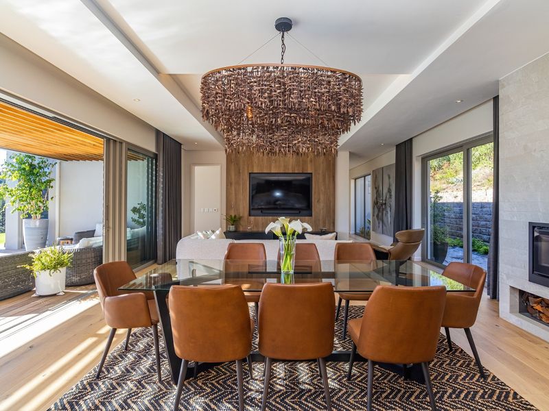Spacious open-plan living and dining area featuring high-end finishes, a built-in fireplace, and seamless indoor-outdoor flow through large sliding glass doors.