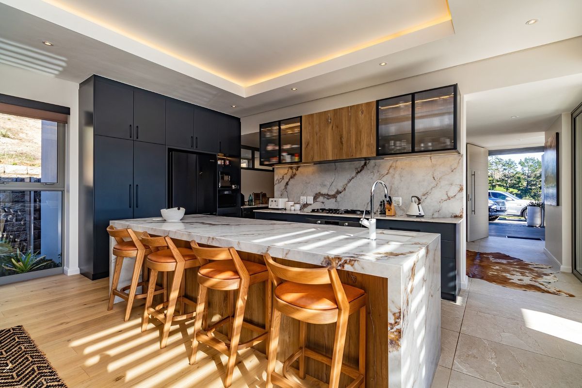 Modern kitchen featuring a marble waterfall island, high-end cabinetry, integrated appliances, and elegant recessed lighting, creating a sophisticated and functional culinary space.