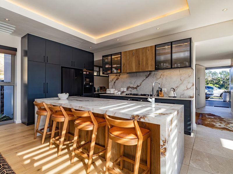 Modern kitchen featuring a marble waterfall island, high-end cabinetry, integrated appliances, and elegant recessed lighting, creating a sophisticated and functional culinary space.